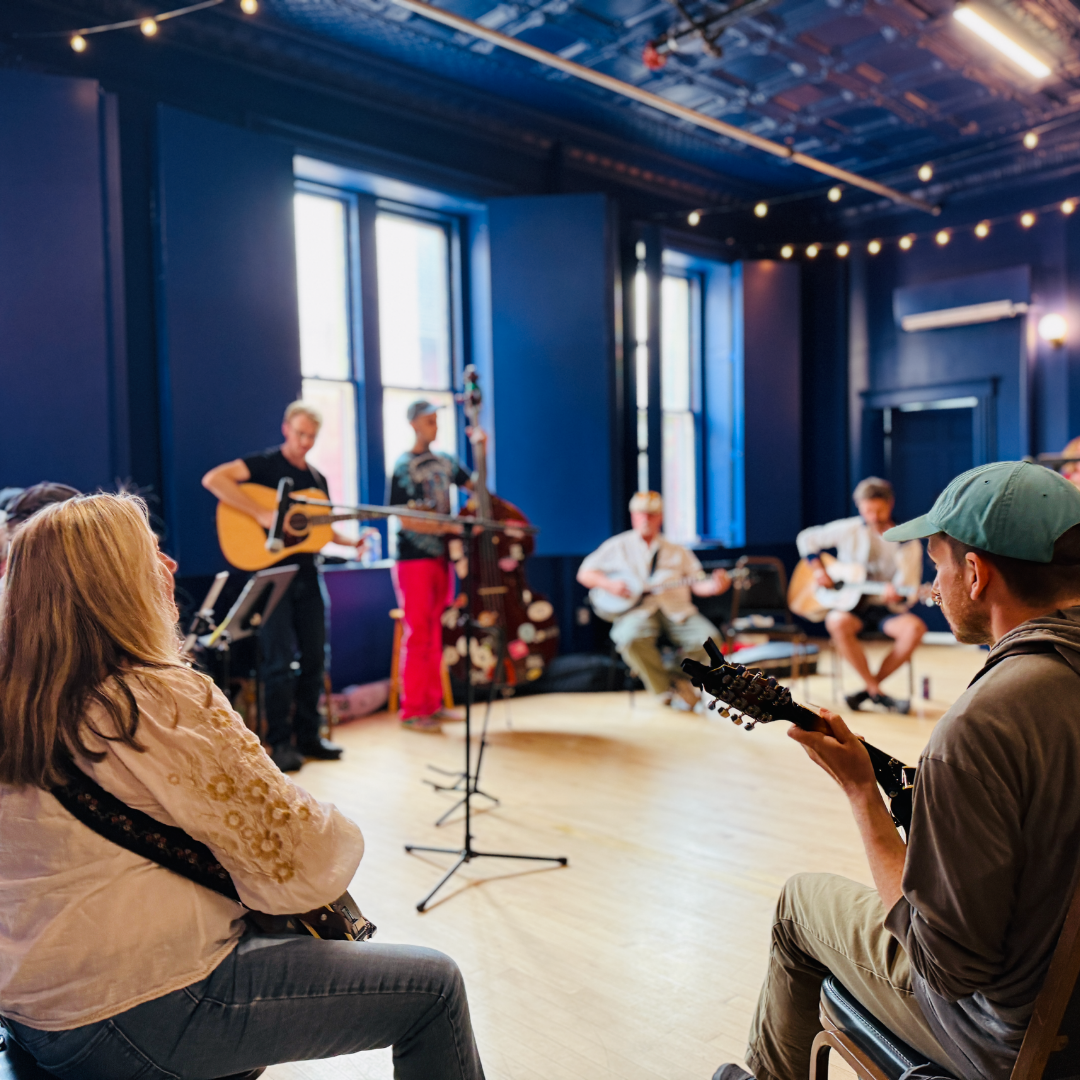 people in a circle playing music on stringed instruments